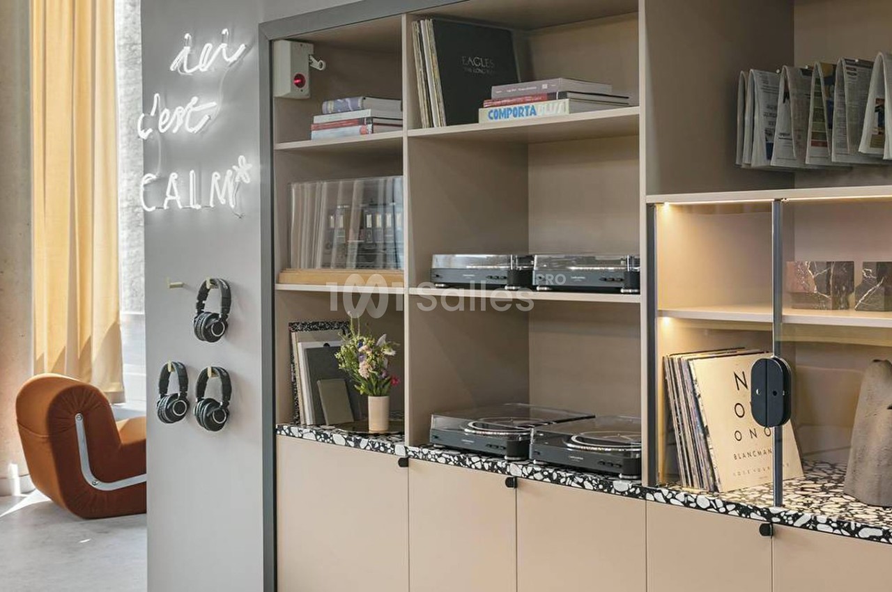 Étagères modernes avec livres, vinyles, casques audio et platines, dans un espace lumineux au design contemporain.