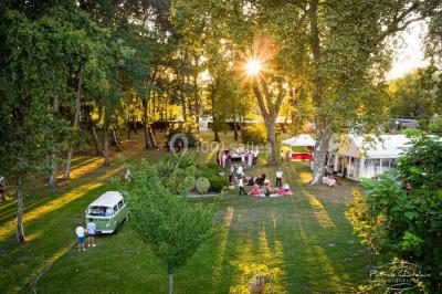 Kiosque décoré de fleurs blanches au bord d'un lac avec une fontaine, sous un ciel dégagé.