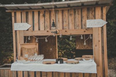 Kiosque décoré de fleurs blanches au bord d'un lac avec une fontaine, sous un ciel dégagé.