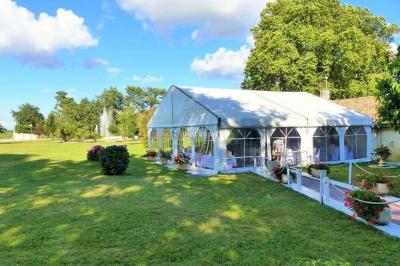 Kiosque décoré de fleurs blanches au bord d'un lac avec une fontaine, sous un ciel dégagé.