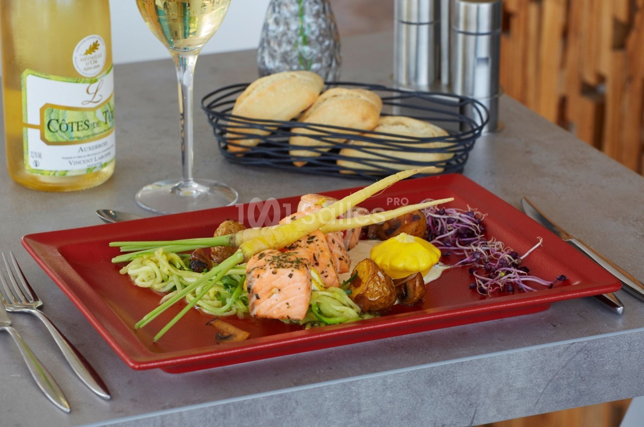 Assiette de saumon grillé avec légumes, purée, pommes de terre rôties et pain, servie avec un verre de vin blanc.
