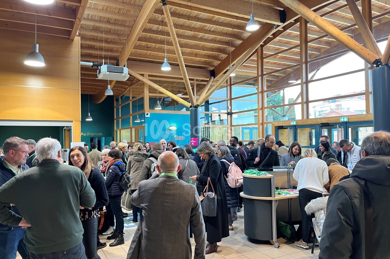Groupe de personnes rassemblées dans un hall lumineux avec une structure en bois et des stands d'information.