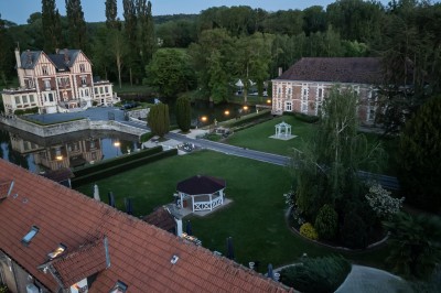 Miniature Location salle Quesmy (Oise) - Château de Quesmy #6 Chambre élégante avec murs bleus, lit double, cheminée, miroir doré, armoire en bois et tapis géométrique.