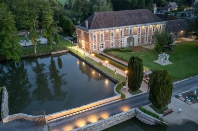 Miniature Location salle Quesmy (Oise) - Château de Quesmy #3 Chambre élégante avec murs bleus, lit double, cheminée, miroir doré, armoire en bois et tapis géométrique.
