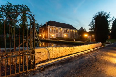 Miniature Location salle Quesmy (Oise) - Château de Quesmy #4 Chambre élégante avec murs bleus, lit double, cheminée, miroir doré, armoire en bois et tapis géométrique.