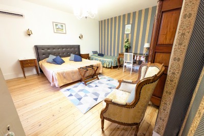 Miniature Location salle Quesmy (Oise) - Château de Quesmy #33 Chambre élégante avec murs bleus, lit double, cheminée, miroir doré, armoire en bois et tapis géométrique.