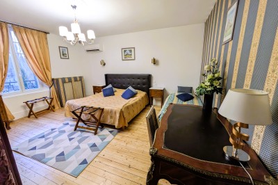 Miniature Location salle Quesmy (Oise) - Château de Quesmy #34 Chambre élégante avec murs bleus, lit double, cheminée, miroir doré, armoire en bois et tapis géométrique.