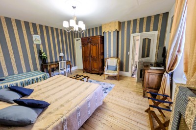 Miniature Location salle Quesmy (Oise) - Château de Quesmy #35 Chambre élégante avec murs bleus, lit double, cheminée, miroir doré, armoire en bois et tapis géométrique.