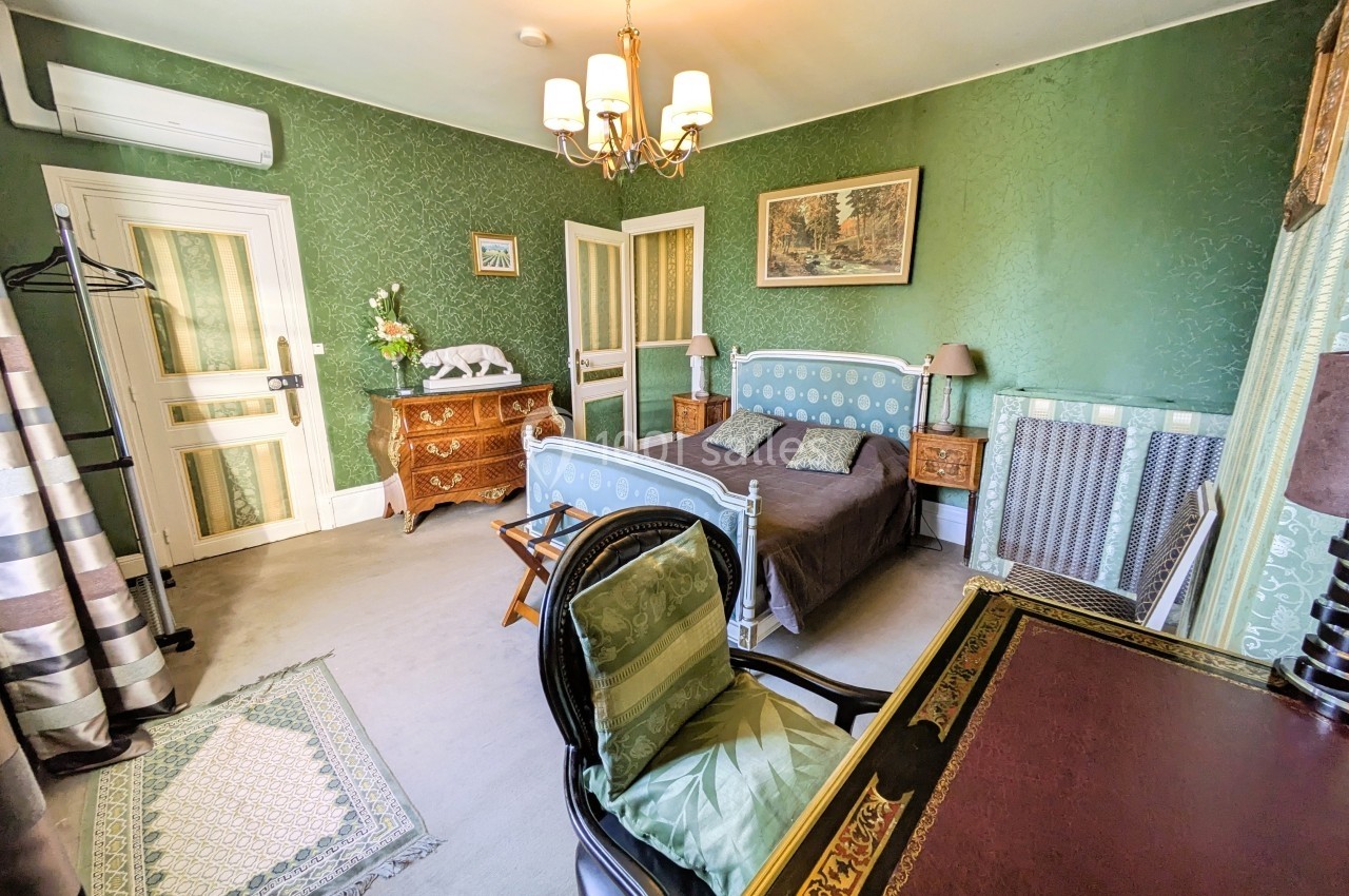 Chambre avec lit simple, bureau, fauteuil, commode et décoration classique dans des tons verts et bois.