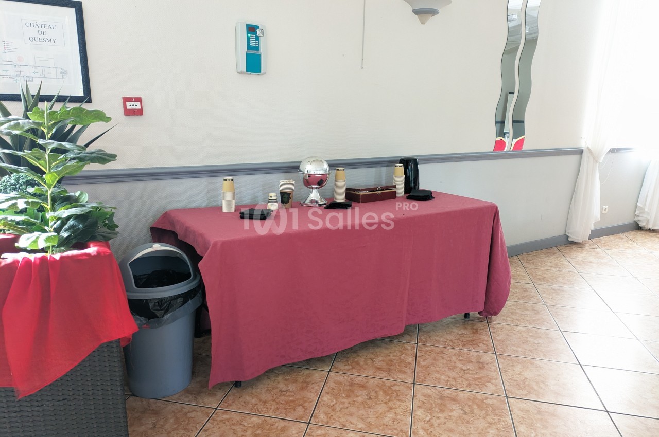 Table recouverte d'une nappe rouge avec des accessoires de service, près d'une plante et d'une poubelle dans une pièce…