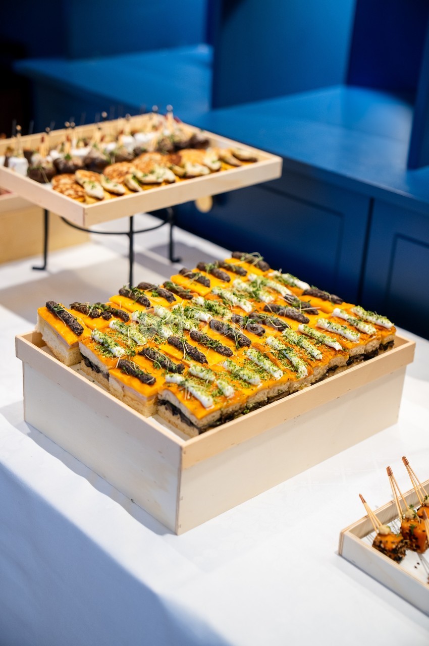 Plateaux de bouchées apéritives colorées disposées sur une table blanche dans un cadre intérieur.