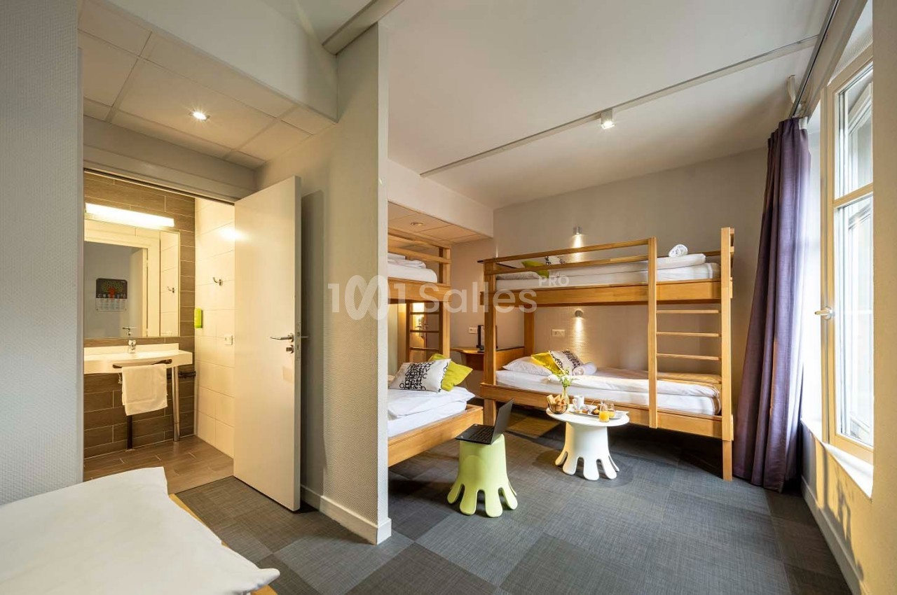 Chambre lumineuse avec lits superposés en bois, salle de bain attenante et grande fenêtre laissant entrer la lumière…