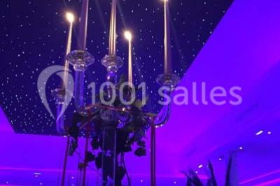 Miniature Location salle Le Raincy (Seine-Saint-Denis) - Le Chalet des Pins #13 Scène de DJ éclairée par des lumières colorées, entourée de rideaux rouges et de haut-parleurs dans une salle.