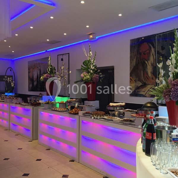 Location salle Le Raincy (Seine-Saint-Denis) - Le Chalet des Pins #16 Buffet lumineux avec plats variés, décoré de fleurs et éclairé par des lumières colorées dans une salle moderne.