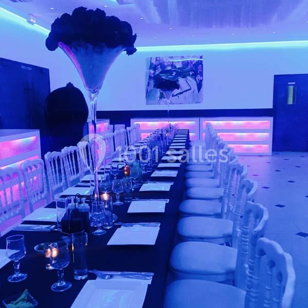 Location salle Le Raincy (Seine-Saint-Denis) - Le Chalet des Pins #3 Salle de réception avec une longue table dressée, éclairage tamisé et décorations lumineuses colorées.