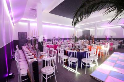 Miniature Location salle Le Raincy (Seine-Saint-Denis) - Le Chalet des Pins #2 Scène de DJ éclairée par des lumières colorées, entourée de rideaux rouges et de haut-parleurs dans une salle.