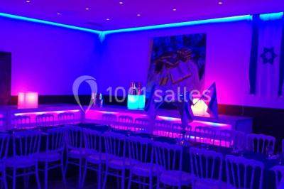 Miniature Location salle Le Raincy (Seine-Saint-Denis) - Le Chalet des Pins #21 Scène de DJ éclairée par des lumières colorées, entourée de rideaux rouges et de haut-parleurs dans une salle.