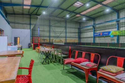 Miniature Location salle Villeneuve-le-Roi (Val-de-Marne) - Le Boston #16 Salle intérieure avec terrain de sport entouré de filets, tables et chaises disposées sur un sol en gazon synthétique.