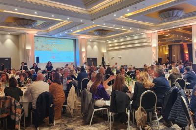 Un public assis dans une salle de conférence, attentif à une présentation sur une scène éclairée.