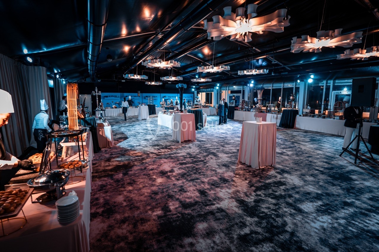 Salle de réception élégante avec tables dressées, buffets et éclairage tamisé pour un événement.