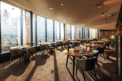 Des invités dînent autour de tables rondes tandis qu'un groupe joue sur une scène illuminée dans une salle de réception.