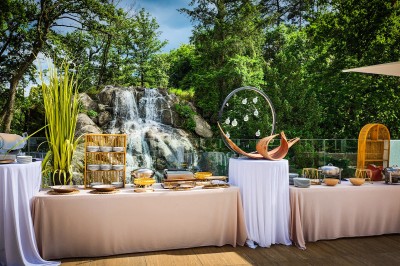 Des invités dînent autour de tables rondes tandis qu'un groupe joue sur une scène illuminée dans une salle de réception.