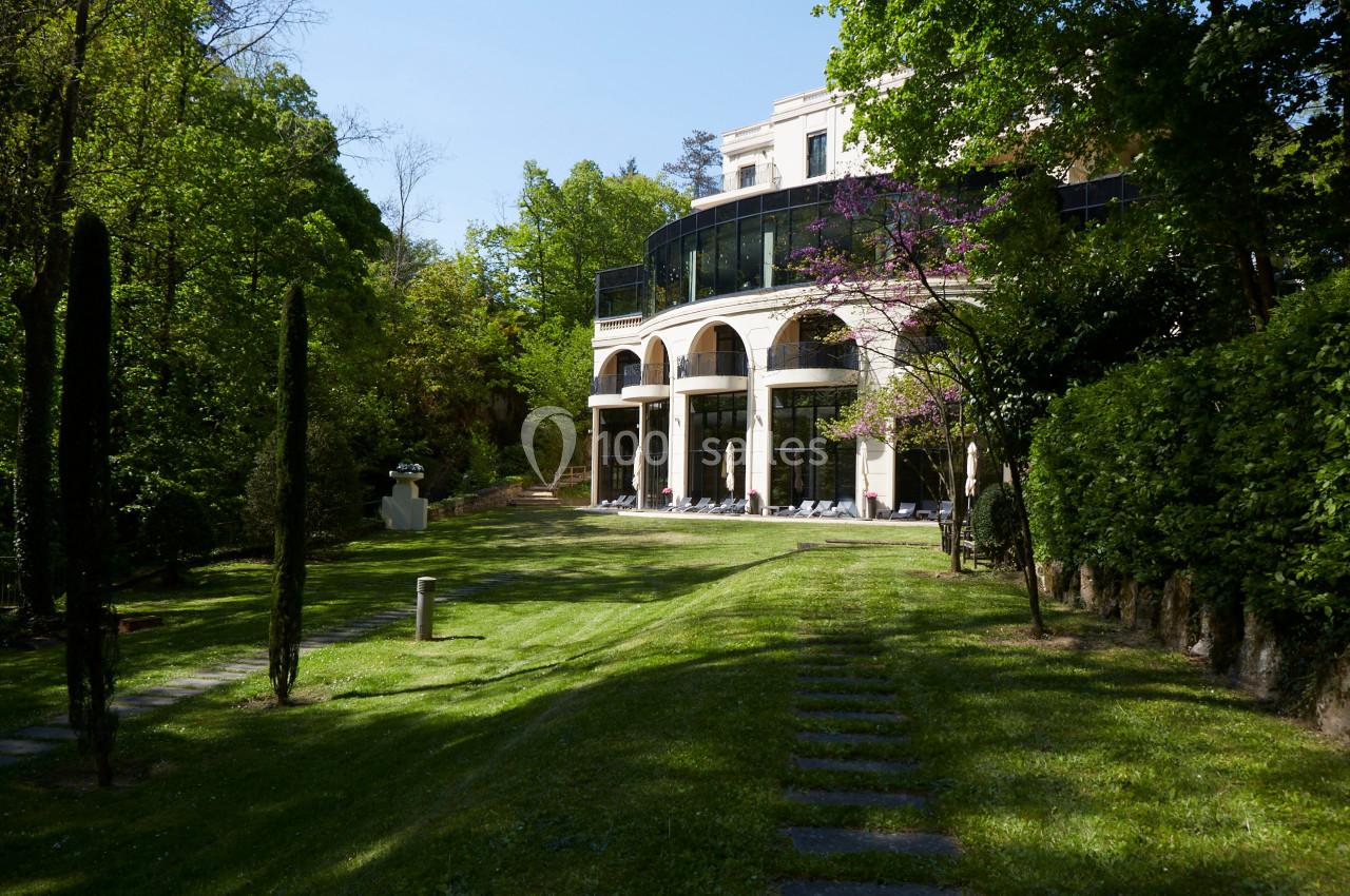 Parc pour Team building (prestataires libres) Façade d'un bâtiment moderne entouré de verdure, avec une pelouse et des arbres sous un ciel dégagé.