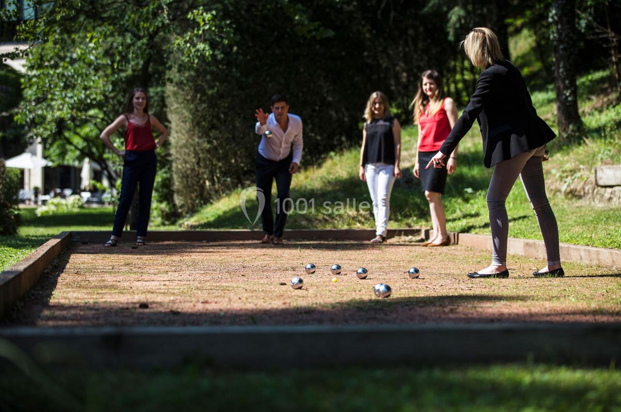 Vos Team Building (prestataires libres) Des personnes jouent à la pétanque sur un terrain en plein air, entouré de verdure.
