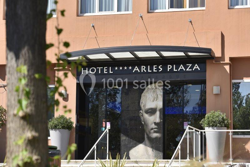 Façade de l'hôtel Arles Plaza avec une entrée vitrée et une grande image artistique en arrière-plan.