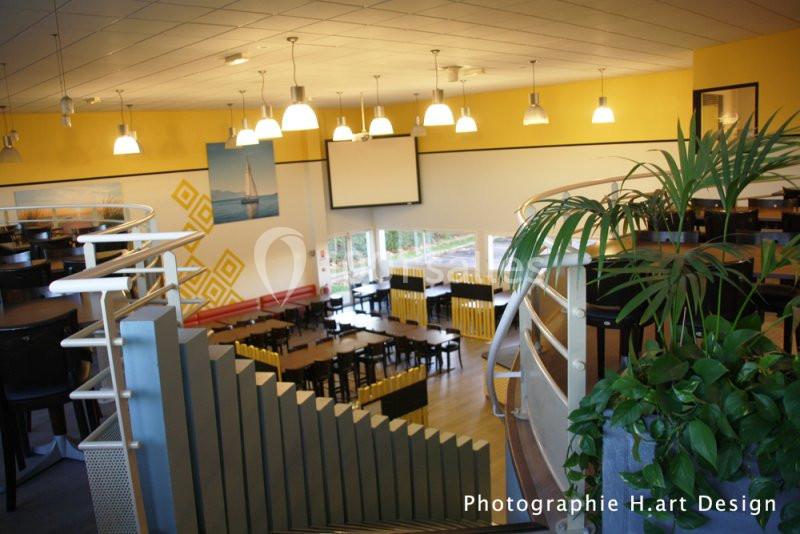 Vue intérieure d'un restaurant lumineux avec des tables, des chaises jaunes et noires, et une décoration moderne.