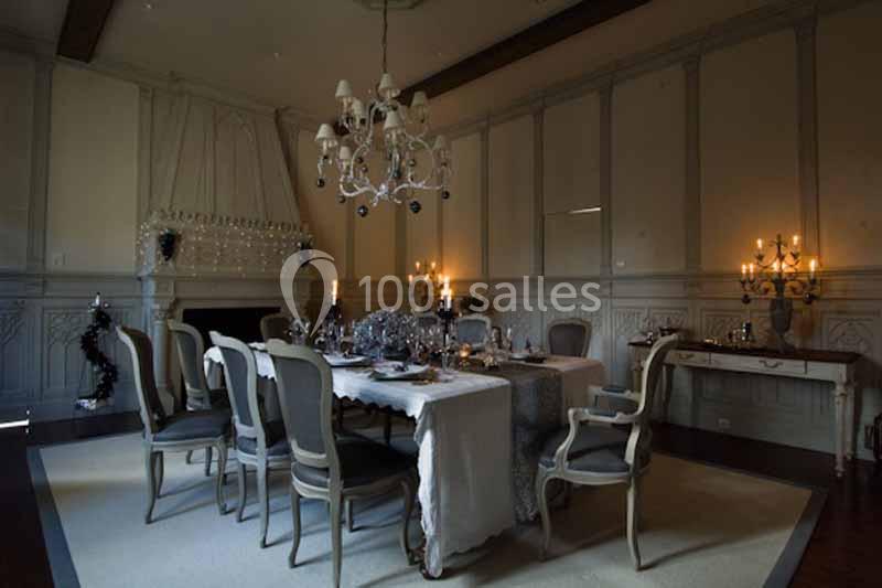 Salle à manger élégante avec table dressée, chandeliers allumés et décoration raffinée dans une ambiance tamisée.