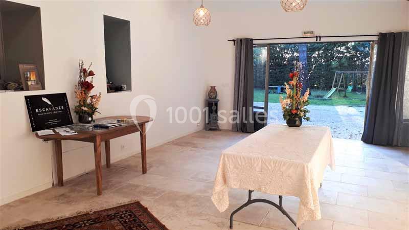 Location salle Caderousse (Vaucluse) - Domaine de la Lusignane #6 Salle lumineuse avec table recouverte d'une nappe, décorations florales et vue sur un jardin avec balançoire.