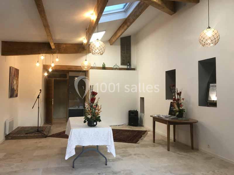 Location salle Caderousse (Vaucluse) - Domaine de la Lusignane #7 Salle lumineuse avec poutres apparentes, tables décorées de fleurs et éclairage suspendu.