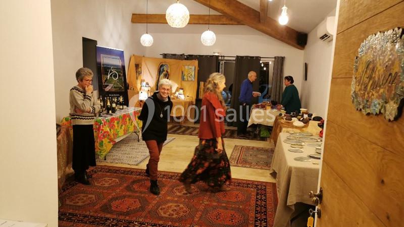 Location salle Caderousse (Vaucluse) - Domaine de la Lusignane #8 Des personnes discutent et se déplacent dans une pièce chaleureuse décorée pour un événement avec des tables dressées.
