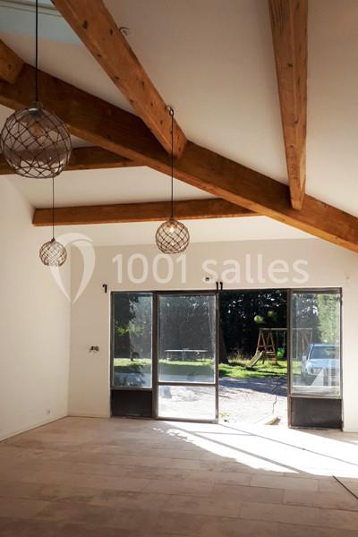 Location salle Caderousse (Vaucluse) - Domaine de la Lusignane #5 Intérieur lumineux avec poutres apparentes, grandes baies vitrées donnant sur un jardin avec balançoire.