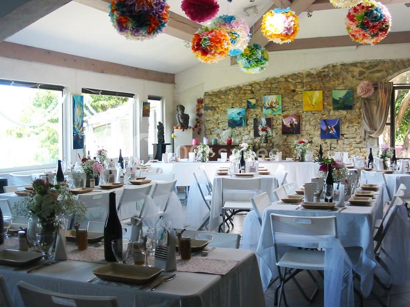 Location salle Caderousse (Vaucluse) - Domaine de la Lusignane #3 Salle de réception décorée avec des tables dressées, des fleurs, des guirlandes colorées et des tableaux au mur.