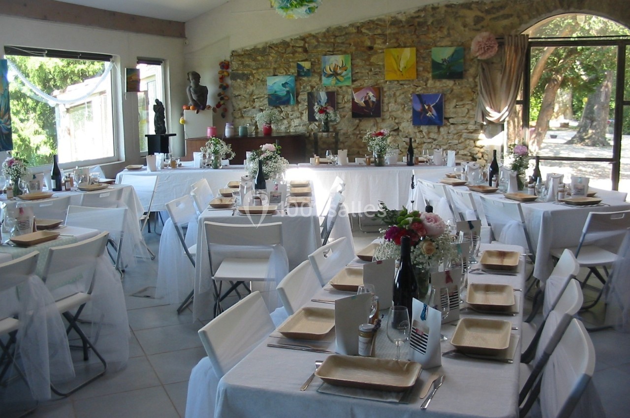 Location salle Caderousse (Vaucluse) - Domaine de la Lusignane #16 Salle de réception décorée avec des tables dressées, nappes blanches, chaises pliantes et ornements colorés.