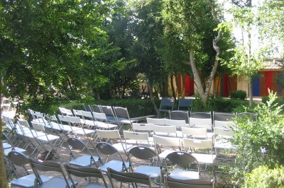 Miniature Location salle Caderousse (Vaucluse) - Domaine de la Lusignane #23 Salle décorée pour un événement, avec des tables alignées, nappes blanches, chemins de table rouges et lanternes suspendues.