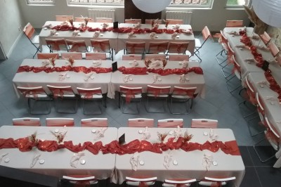 Miniature Location salle Caderousse (Vaucluse) - Domaine de la Lusignane #24 Salle décorée pour un événement, avec des tables alignées, nappes blanches, chemins de table rouges et lanternes suspendues.