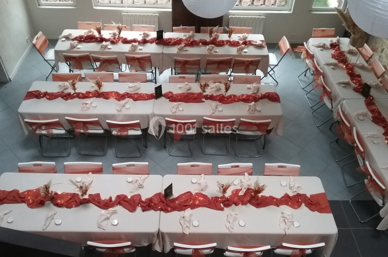 Location salle Caderousse (Vaucluse) - Domaine de la Lusignane #24 Salle décorée pour un événement, avec des tables alignées, nappes blanches et chemins de table rouges ornés de décorations.