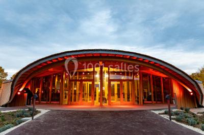 Terrasse extérieure avec tables rondes, chaises pliantes et guirlandes lumineuses suspendues, ambiance en soirée.
