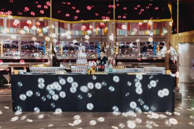 Terrasse extérieure avec tables rondes, chaises pliantes et guirlandes lumineuses suspendues, ambiance en soirée.