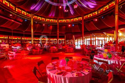 Terrasse extérieure avec tables rondes, chaises pliantes et guirlandes lumineuses suspendues, ambiance en soirée.