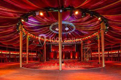 Terrasse extérieure avec tables rondes, chaises pliantes et guirlandes lumineuses suspendues, ambiance en soirée.