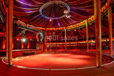 Terrasse extérieure avec tables rondes, chaises pliantes et guirlandes lumineuses suspendues, ambiance en soirée.
