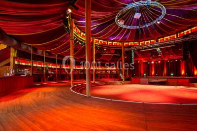 Terrasse extérieure avec tables rondes, chaises pliantes et guirlandes lumineuses suspendues, ambiance en soirée.