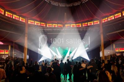 Terrasse extérieure avec tables rondes, chaises pliantes et guirlandes lumineuses suspendues, ambiance en soirée.