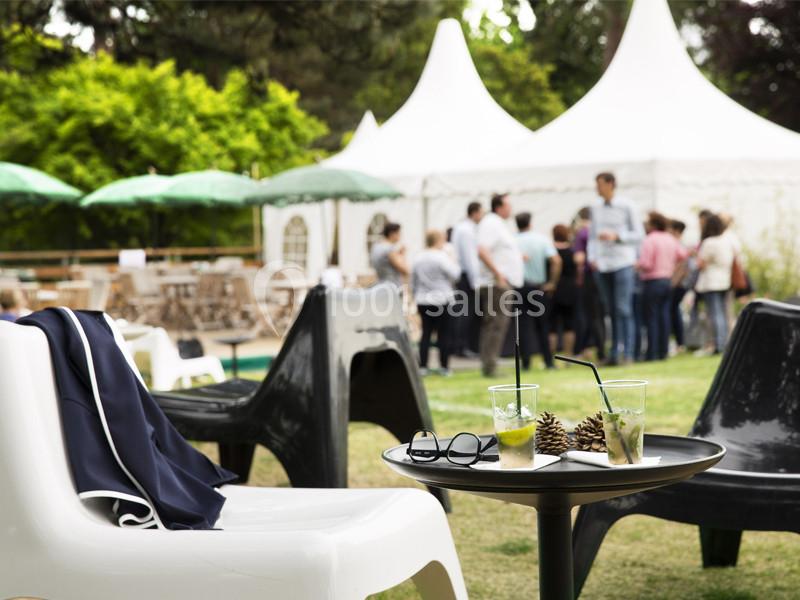 Location salle Louveciennes (Yvelines) - Campus BNP Paribas Louveciennes #23 Des chaises et une table avec des boissons en extérieur, devant des tentes blanches et un groupe de personnes.