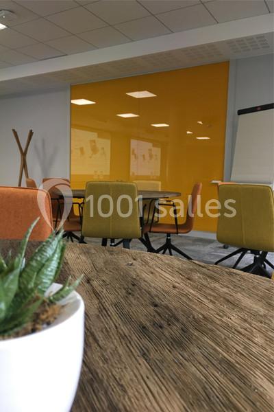 Location salle Louveciennes (Yvelines) - Campus BNP Paribas Louveciennes #10 Salle de réunion moderne avec table en bois, chaises colorées, mur jaune, tableau de conférence et plante au premier plan.