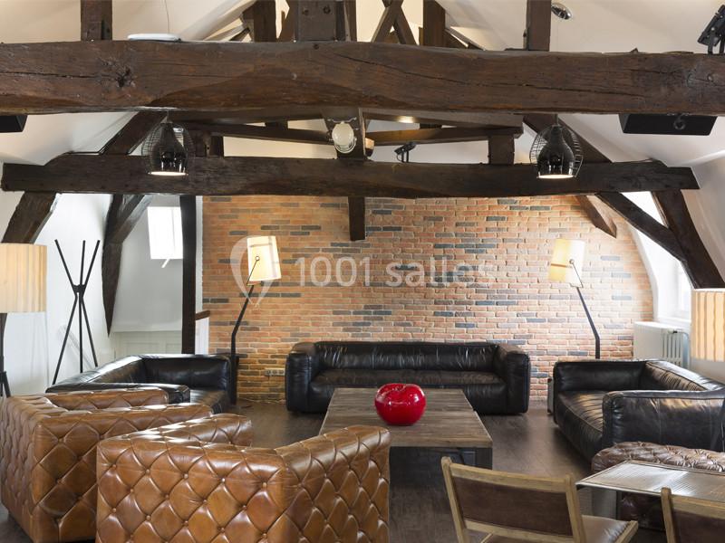Location salle Louveciennes (Yvelines) - Campus BNP Paribas Louveciennes #15 Salon avec poutres apparentes, murs en briques, fauteuils en cuir et table basse en bois, éclairé par des lampes modernes.